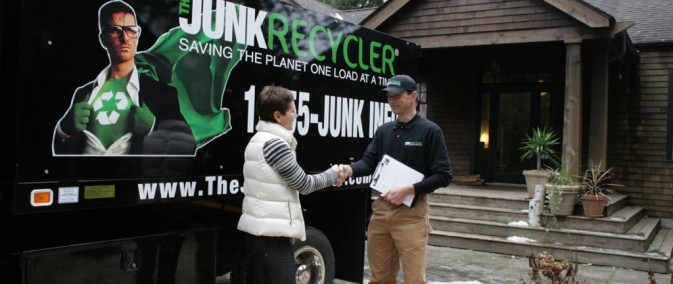 Two people shaking hands in front of a junk removal truck.