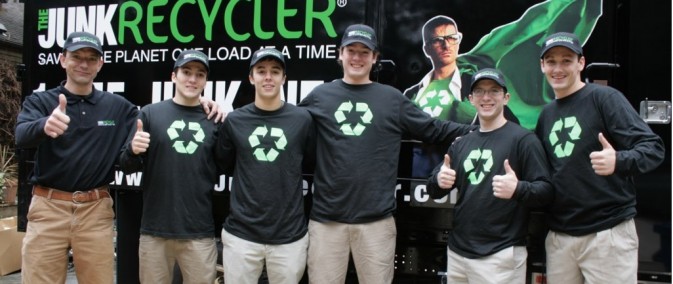 A group of men standing in front of a junk recycler truck.